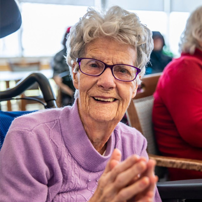 Elderly woman sits smiling at camera