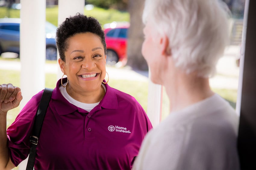 Home Instead caregiver greets senior woman at front door